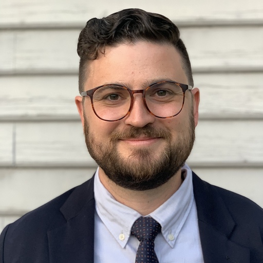 Photo of Will Pfeffer smiling in a suit and tie